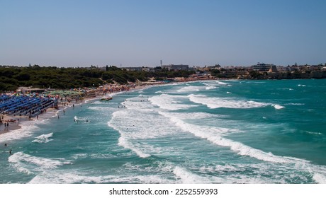 Torre dell'Orso beach in Lecce, Italy. Beach between cliffs crowded with umbrellas and bathers looking to cool off in its warm turquoise waters during the summer. - Shutterstock ID 2252559393