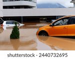 Torrential rain causes flash floods in the city area. Cars under water in the condominium parking lot. Damaged cars caused by heavy rainfall. Buildings surrounded by water.