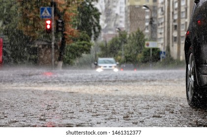 Torrential Rain At Crossroads And Red Light Reflected In The Flow Of Water On A City Street.