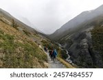 Torres del Paine National Park, Patagonia, Chile; hikers walking towards the lookout point for the three iconic granite towers (torres) on the W-trek route surrounded by mountains