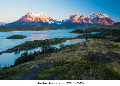 Torres del Paine National Park, lake of Pehoe with islets during sunrise. Two photographers are visible on top of the hill at right part of the frame