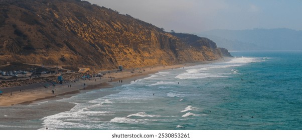 Torrey Pines State Beach in San Diego features rugged golden cliffs, a deep blue Pacific Ocean, and people enjoying the shoreline with lifeguard towers. - Powered by Shutterstock