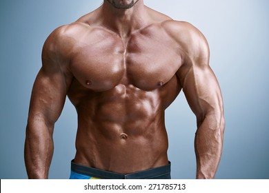 Torso Of Attractive Male Body Builder On Blue Background.