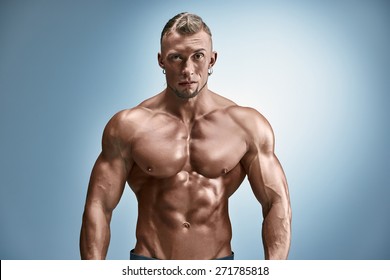 Torso Of Attractive Male Body Builder On Blue Background.