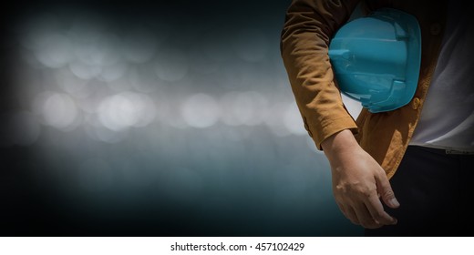 Torso engineer, worker or architect holding plastic helmet in hand on abstract pastel blurred background.