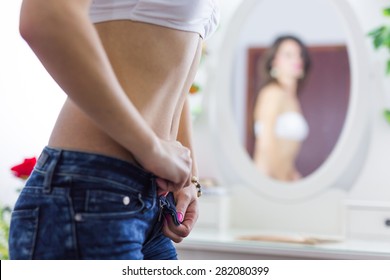 Torso Of A Fit Woman Undressing The Jeans And Looking In The Mirror