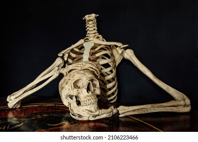 Torso of a human skeleton holding it's own skull