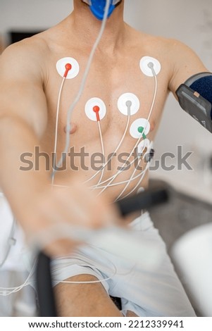 Torso of man athlete with electrodes, testing heart system on bike simulator