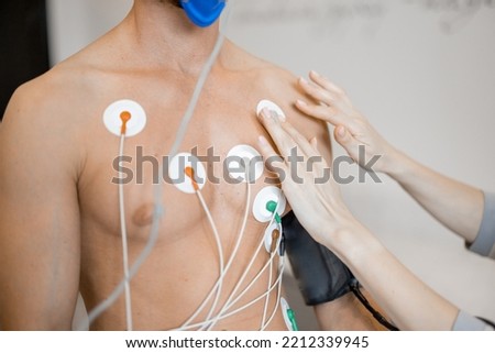 Torso of man athlete with electrodes, testing heart system on bike simulator