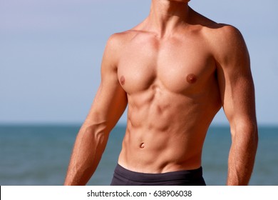 Torso Of Young Muscular Man At The Sea. Sculpted Abs And Athletic Body.