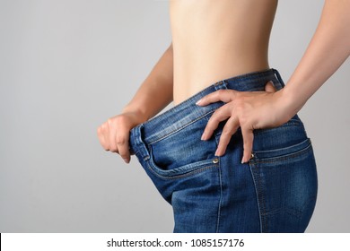 Torso of a young slim woman in big jeans. Results after training and diet.