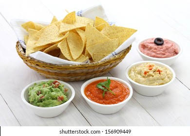 tortilla chips with four super bowl dips which are salsa roja, guacamole, taramasalata, and hummus. - Powered by Shutterstock