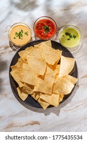 Tortilla Chips Tomato And Guacamole Salsa With Queso Mexican Cheese Dip On Marble Kitchen Table