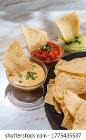 Tortilla Chips Tomato And Guacamole Salsa With Queso Mexican Cheese Dip On Marble Kitchen Table