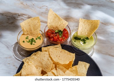 Tortilla Chips Tomato And Guacamole Salsa With Queso Mexican Cheese Dip On Marble Kitchen Table