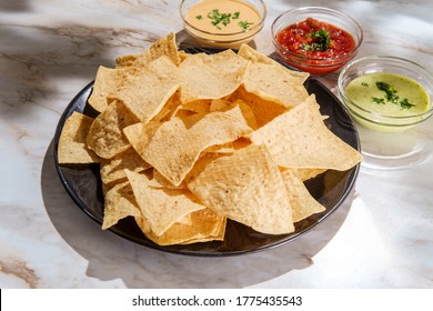 Tortilla Chips Tomato And Guacamole Salsa With Queso Mexican Cheese Dip On Marble Kitchen Table