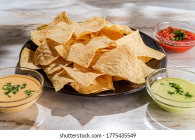 Tortilla Chips Tomato And Guacamole Salsa With Queso Mexican Cheese Dip On Marble Kitchen Table