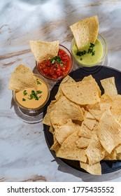 Tortilla Chips Tomato And Guacamole Salsa With Queso Mexican Cheese Dip On Marble Kitchen Table