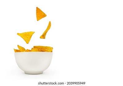 Tortilla Corn Chips Are Falling Into A White Ceramic Bowl On A White Background With Place For Text.