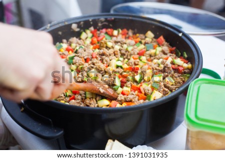 Tortillas filling frying in the electric pan while a woman hand is stirring with a spatula