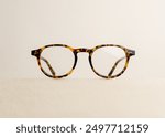 Tortoise round glasses isolated on beige background. Minimalist glasses display with copy space for text.