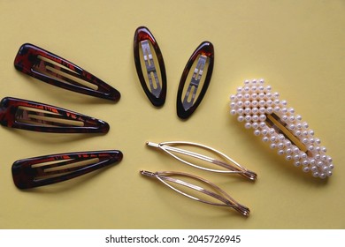 Tortoise Shell, Golden And Pearl Hair Accessories On Yellow Background. Flat Lay.