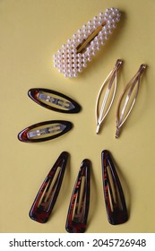 Tortoise Shell, Golden And Pearl Hair Accessories On Yellow Background. Flat Lay.