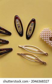 Tortoise Shell, Golden And Pearl Hair Accessories On Yellow Background. Flat Lay.