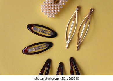 Tortoise Shell, Golden And Pearl Hair Accessories On Yellow Background. Flat Lay.