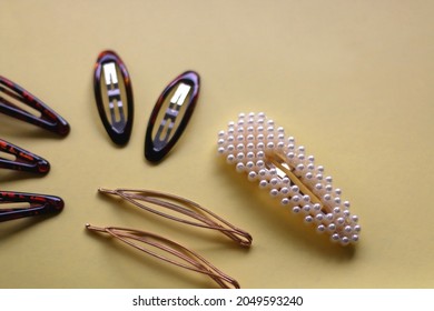 Tortoise Shell, Golden And Pearl Hair Accessories On Yellow Background. Selective Focus.