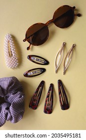 Tortoise Shell Sunglasses And Various Hair Accessories On Yellow Background. Flat Lay.