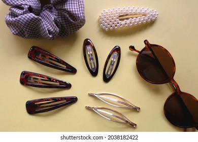 Tortoise Shell Sunglasses And Various Hair Accessories On Yellow Background. Flat Lay.