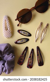 Tortoise Shell Sunglasses And Various Hair Accessories On Yellow Background. Flat Lay.