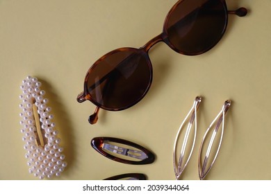 Tortoise Shell Sunglasses And Various Hair Accessories On Yellow Background. Flat Lay.