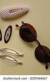 Tortoise Shell Sunglasses And Various Hair Accessories On Yellow Background. Flat Lay.