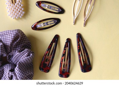 Tortoise Shell Sunglasses And Various Hair Accessories On Yellow Background. Flat Lay.