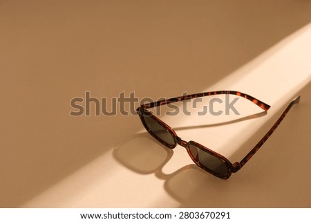 Tortoiseshell sunglasses casting shadow on beige surface