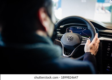 Tortosa, Spain; 01, 22, 2021: Man holding black steering wheel with latest generation Volkswagen golf logo of German car manufacturer Volkswagen while at the dealership.  screen with the gps