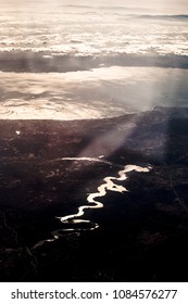 The tortuous riverbed that flows into the sea is very far away. The sun reflects in the water.
