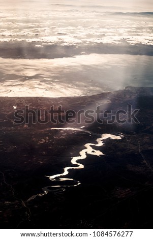 The tortuous riverbed that flows into the sea is very far away. The sun reflects in the water.