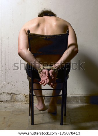 Tortured man on a chair with tied hands. Vertical