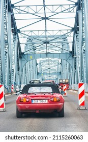 Torun, Poland - August 11, 2021. Reconstruction of Jozef Pilsudski bridge over Wisla river in Summer with old red Mazda MX5 Miata