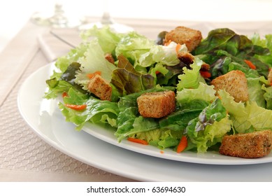 A Tossed Green Salad With Croutons On A Plate