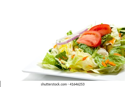 tossed salad including tomatoes, lettuce, romaine, onion, carrots on a white china plate on a white background with copy space