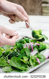 Tossing and serving a healthy green salad with spinach, broccoli and seeds