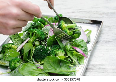 Tossing and serving a healthy green salad with spinach, broccoli and seeds