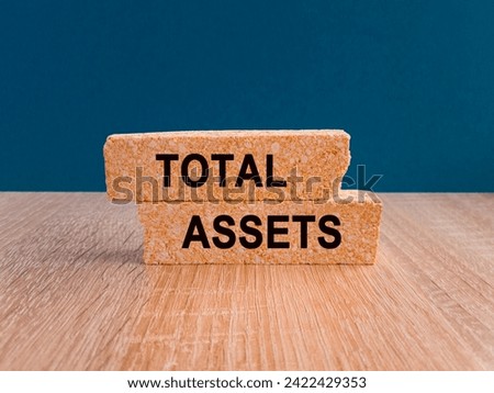 Total assets concept with letters on brick blocks. Beautiful wooden table blue background. Copy space. Capital investment and financial analytics.