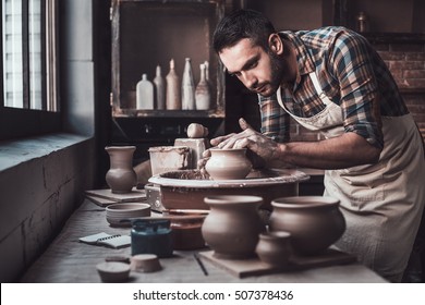 Total Concentration At Work. Confident Young Man Making Ceramic Pot On The Pottery Wheel