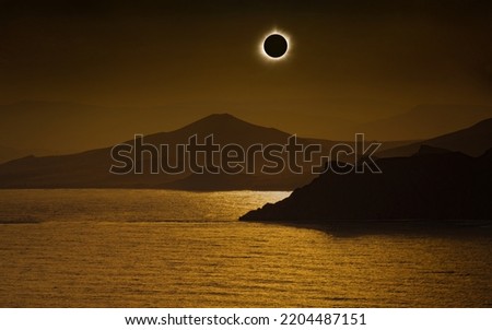 Total solar eclipse in dark red sky above mountains and sea. Eclipse is mysterious natural phenomenon when Moon passes between planet Earth and Sun. Elements of this image furnished by NASA