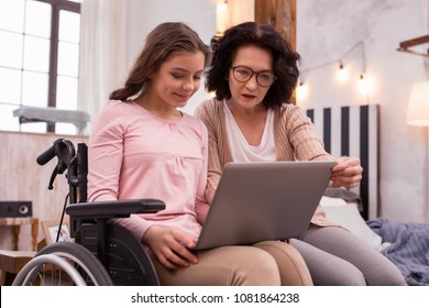 Totally accessible. Attractive immobile girl and woman using laptop while gazing at screen